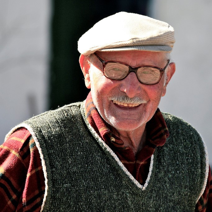 A fit looking older gentleman stands smiling in the sunshine.