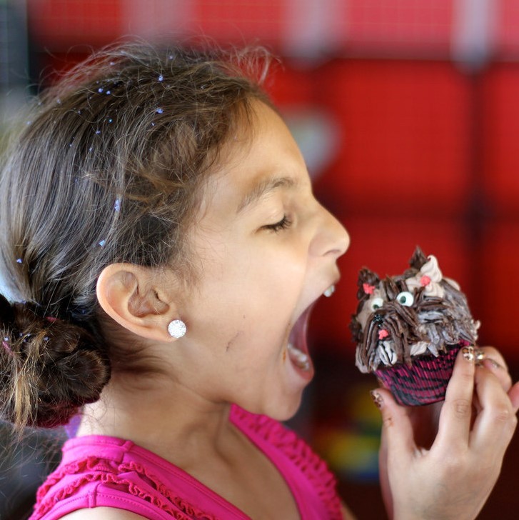 A girls prepares to take a big bite out of a cupcake.