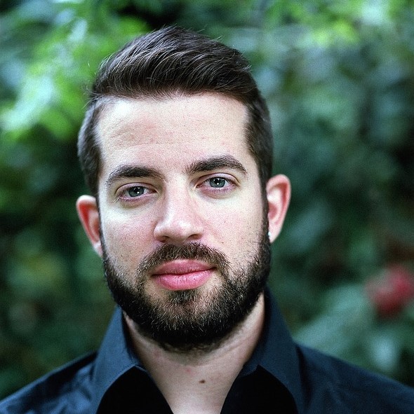 A calm looking man stares coolly into the camera.