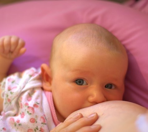 An infant breastfeeds. An infant breastfeeds.