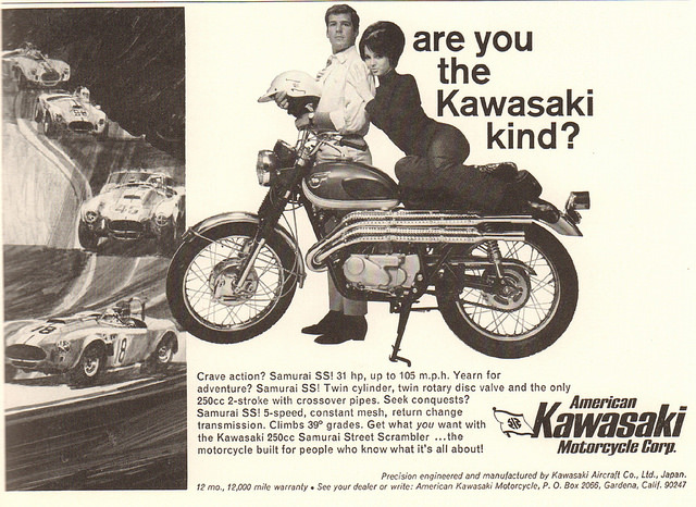 An advertisement for Kawasaki motorcycles from the 1970's. The slogan is "Are You the Kawasaki Kind?" The ad features an average looking man dressed in a shirt and tie standing behind a Kawasaki motorcycle and holding a motorcycle helmet. An attractive woman sits on the seat of the motorcycle and leans her head on the man's shoulder. An advertisement for Kawasaki motorcycles from the 1970's. The slogan is "Are You the Kawasaki Kind?" The ad features an average looking man dressed in a shirt and tie standing behind a Kawasaki motorcycle and holding a motorcycle helmet. An attractive woman sits on the seat of the motorcycle and leans her head on the man's shoulder.
