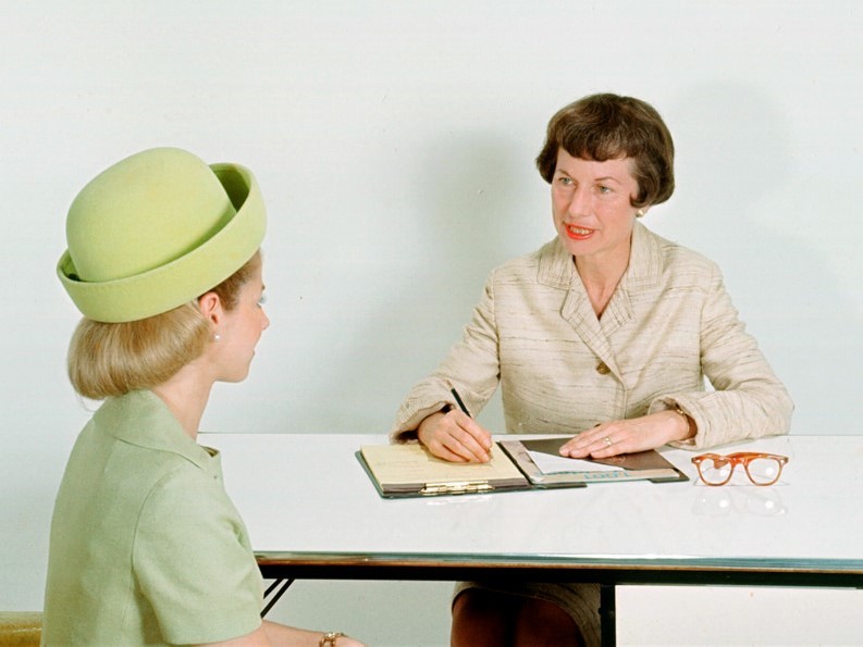 Two women sit across a table from one another during a job interview. Two women sit across a table from one another during a job interview.