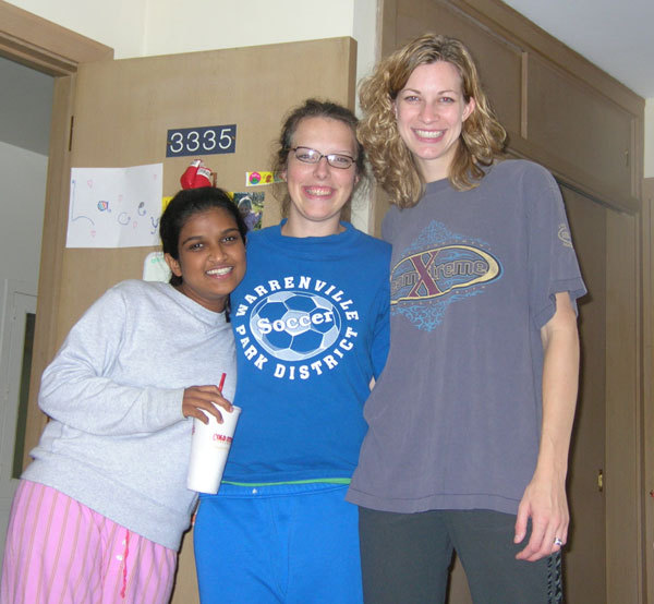 Three college friends stand together in a dorm room. The woman on the right is 6 inches taller than the woman in the middle. The woman in the middle is six inches taller than the woman on the left. Three college friends stand together in a dorm room. The woman on the right is 6 inches taller than the woman in the middle. The woman in the middle is six inches taller than the woman on the left.