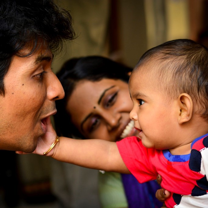 A baby reaches out to touch the face of his smiling father as a happy mother looks on. A baby reaches out to touch the face of his smiling father as a happy mother looks on.